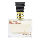 Een heldere rechthoekige glazen fles manasib eau de parfum met zwarte geometrische dop en goudkleurige kraag met lichtgele vloeistof