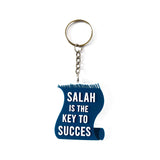 Blauwe acryl sleutelhanger in de vorm van een opgerolde rol met witte tekst salah is the key to succes en versleten rand