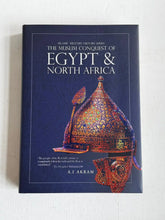Een rijk versierde helm met goud en kleurrijke patronen op een donkerblauwe omslag van het boek the muslim conquest of egypt and north africa