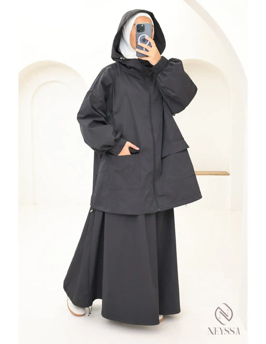 Zwart hooded jas met gelaagde, volumineuze mouwen en een vloeiende rok als onderdeel van een waterafstotende dames set