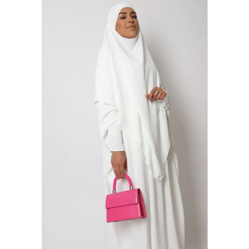 Vrouw in witte hijab en jurk met een felle roze handtas bij Abaya en Khimarset Butterfly