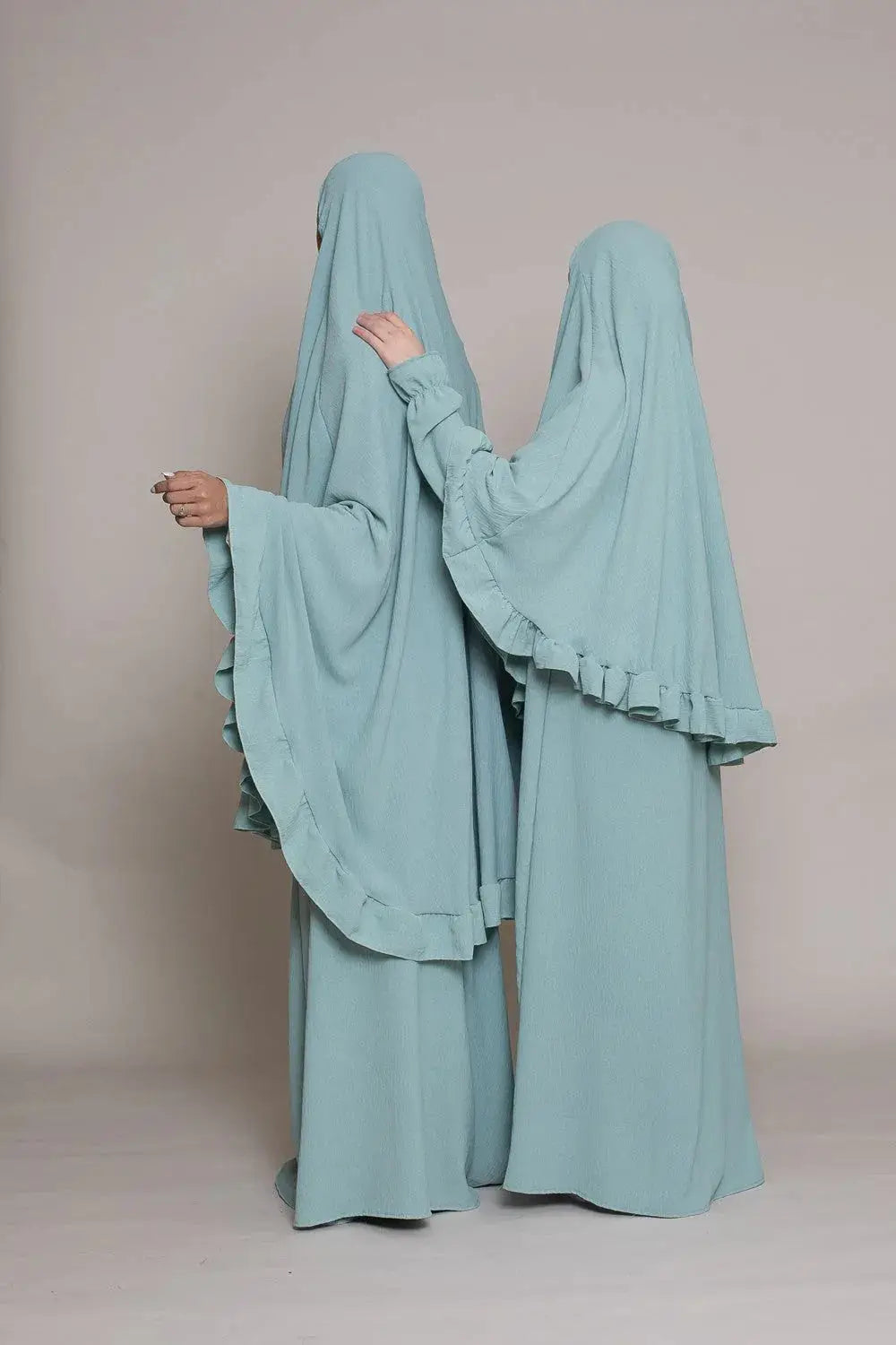 Twee vrouwen dragen bijpassende lichtblauwe abaya en khimarset met vloeiende ruches en lange zoom