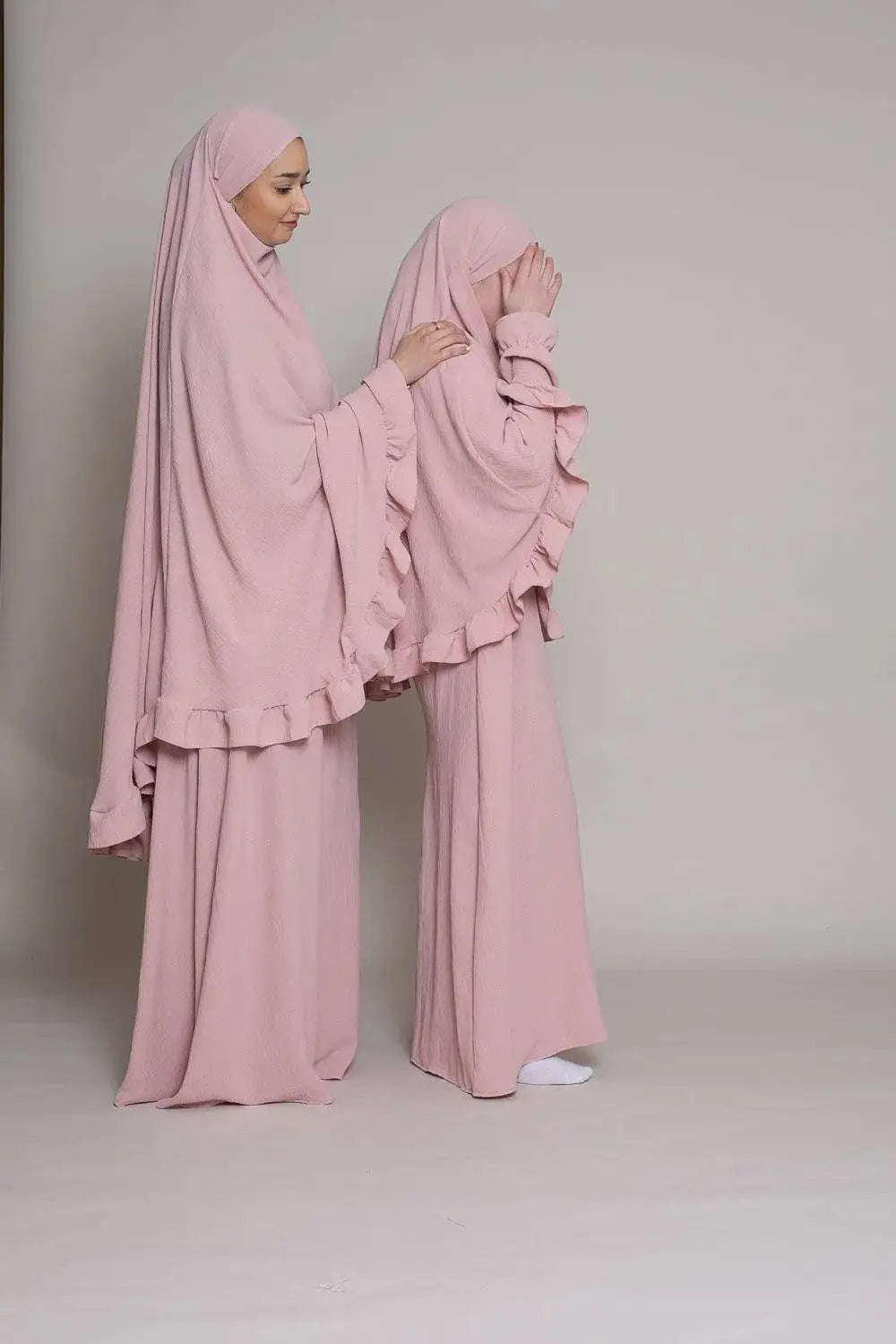 Een zachte roze, vallende hijab met gerimpelde randen gedragen door een vrouw in abaya en khimarset ruffle binti