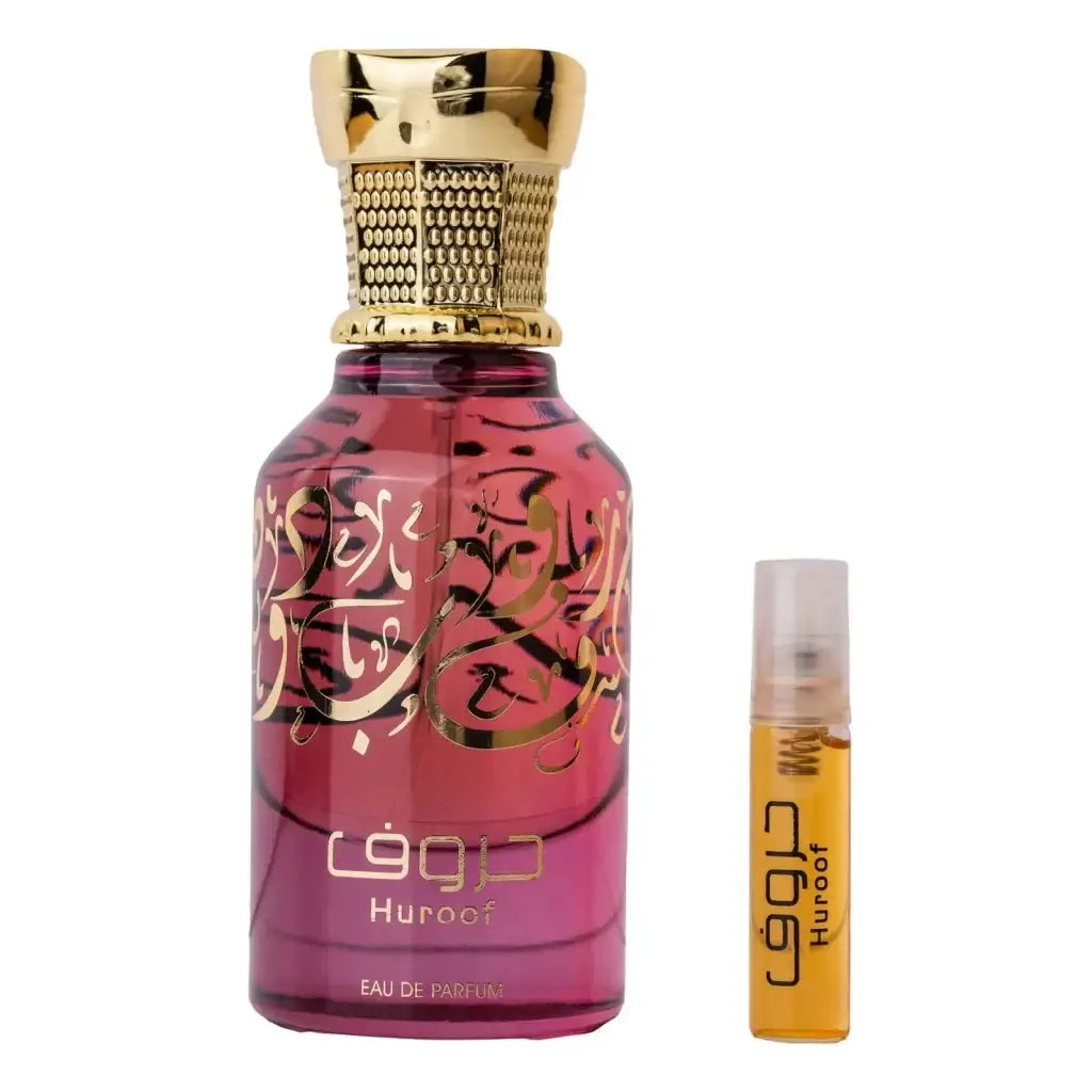 Een levendige roze glazen parfumfles ard al zaafaran huroof met gouden arabische kalligrafie en textuur gouden dop naast een kleine oranje reisflesje