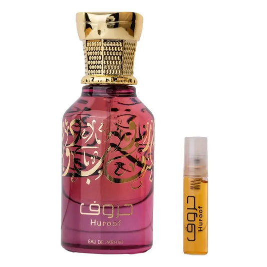 Een levendige roze glazen parfumfles ard al zaafaran huroof met gouden arabische kalligrafie en textuur gouden dop naast een kleine oranje reisflesje