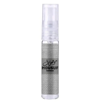 Een heldere glazen sprayfles met een zilverkleurige stoffen wrap en een grijs etiket van mousuf ramadi