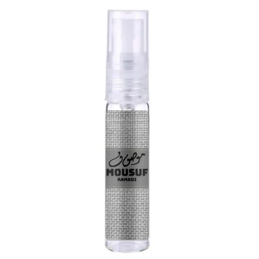 Een heldere glazen sprayfles met een zilverkleurige stoffen wrap en een grijs etiket van mousuf ramadi