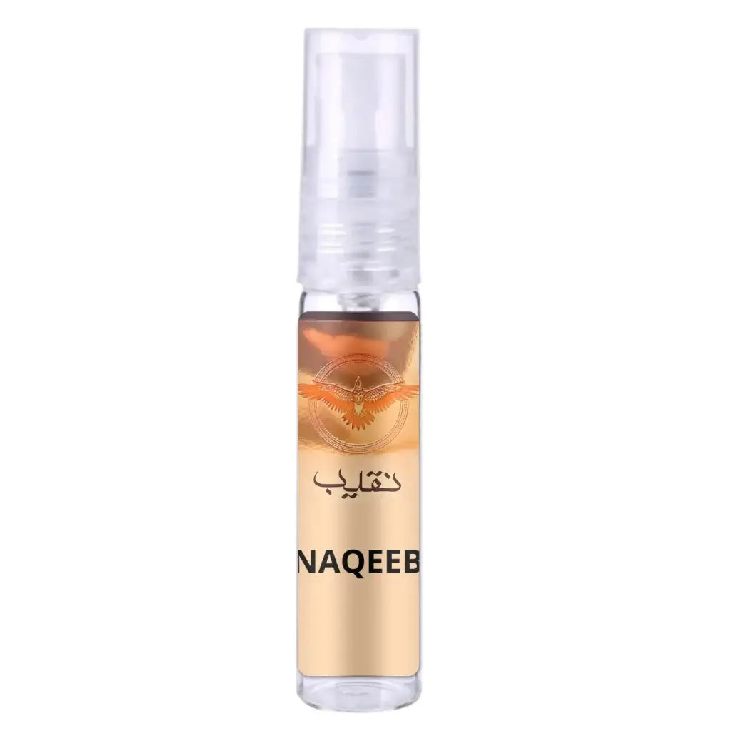 Een transparante glazen sprayfles met amberkleurige vloeistof en een goudkleurig label met oranje vogel en naqeeb tekst