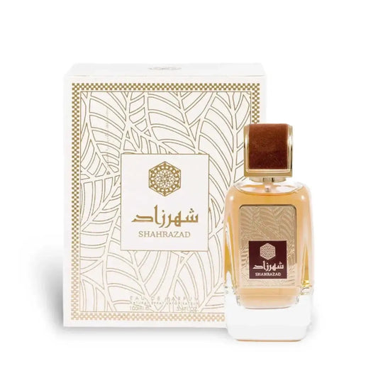 Een rechthoekige glazen fles ard al zaafaran shahrazad parfum met gouden dop en amberkleurige vloeistof naast een witte doos met gouden bladvormpatronen