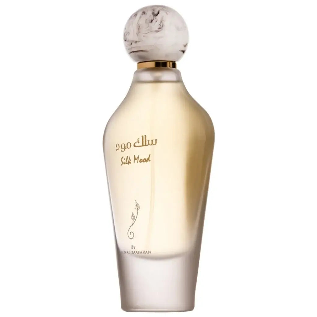 Een slanke transparante glazen fles silk mood parfum van al zaafaran met een marmeren bolvormige dop en gouden accenten
