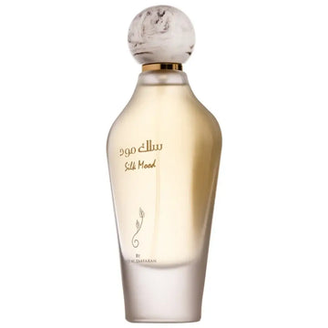 Een slanke transparante glazen fles silk mood parfum van al zaafaran met een marmeren bolvormige dop en gouden accenten