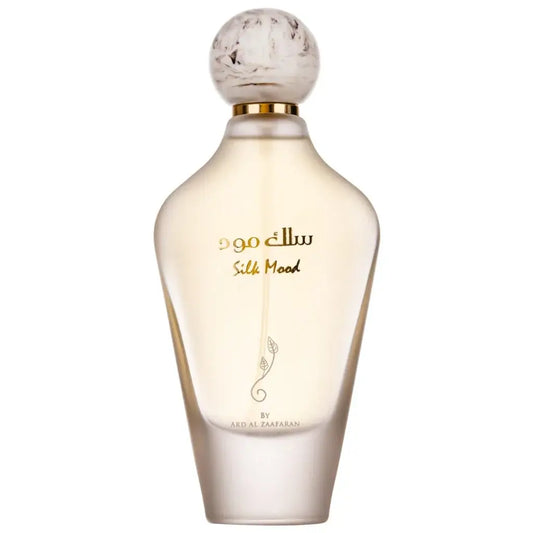 Een slanke doorzichtige glazen parfumfles met een ronde gouden accenten dop en arabische tekst van ard al zaafaran silk mood