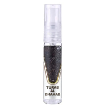 Een heldere glazen sprayfles met een zwart, sierlijk gegraveerd label met gouden rand en tekst turab al dhahab