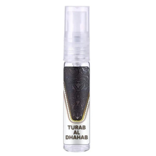 Een heldere glazen sprayfles met een zwart, sierlijk gegraveerd label met gouden rand en tekst turab al dhahab