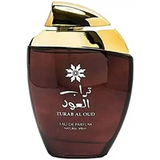 Een slanke donkere amberkleurige glazen fles met een gepolijste gouden dop en gegraveerd arabisch opschrift turab al oud van ard al zaafaran