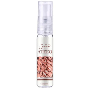 Een transparante glazen sprayfles met een duidelijke pomp en een etiket met de merknaam ateeq en roségouden munten voor ateeq edp 100 ml