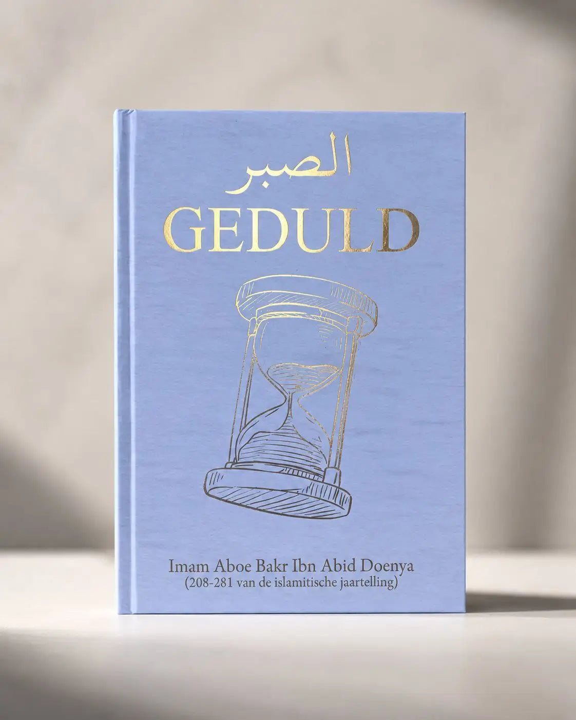 Lichtblauw hardcover boek geduld met gouden folieletters en zandloper illustratie op de cover