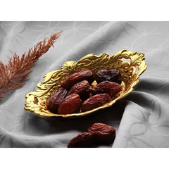 Gouden serveerschaal druppel met donkere rode dadels voor het serveren van dadels suikergoed en turks fruit
