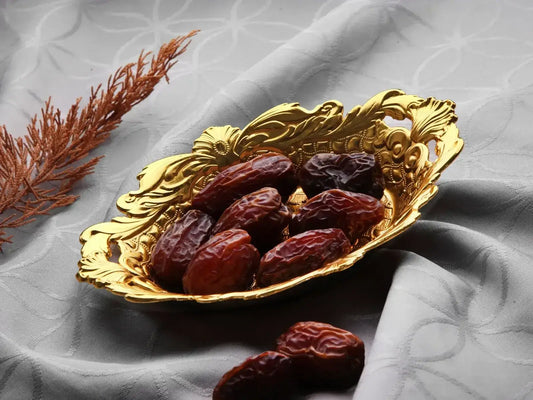 Gouden serveerschaal druppel met donkere rode dadels voor het serveren van dadels suikergoed en turks fruit