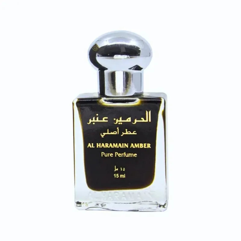 Een slanke transparante glazen fles met een zilverkleurige dop en zwart etiket met gouden arabische tekst voor al haramain amber parfumolie