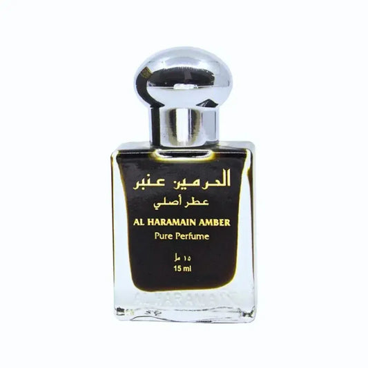 Een slanke transparante glazen fles met een zilverkleurige dop en zwart etiket met gouden arabische tekst voor al haramain amber parfumolie