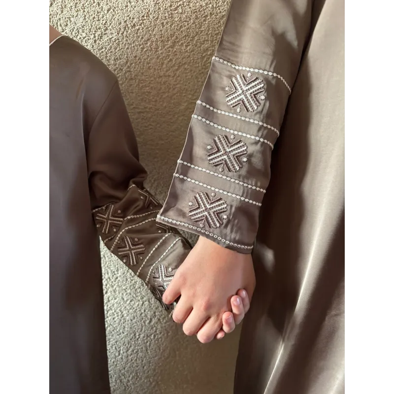 Bruine geborduurde abaya met witte kruispatronen en bijpassende manchetten van Kaftan Sara Binti