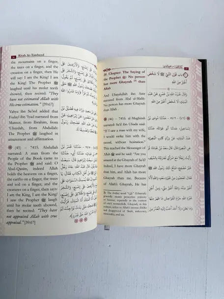 Open book kitab at-tawheed by imam al-bukhari with bilingual english and arabic text and dark blue cover