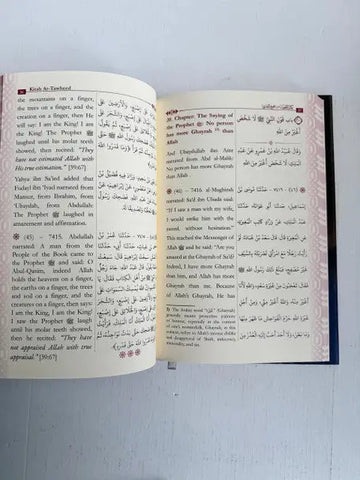 Open book kitab at-tawheed by imam al-bukhari with bilingual english and arabic text and dark blue cover