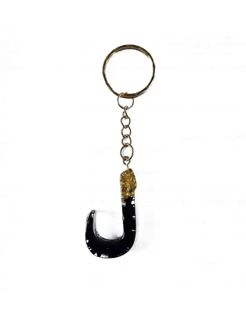 Zwarte resin sleutelhanger in de vorm van de letter j met een goudkleurige ingebedde edelsteen laam arabisch alfabet