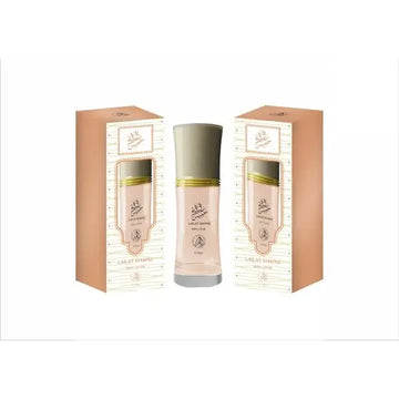 Een slanke doorzichtige glazen fles met bleekroze parfum en zilveren dop met gouden banden voor lailat khamis body lotion