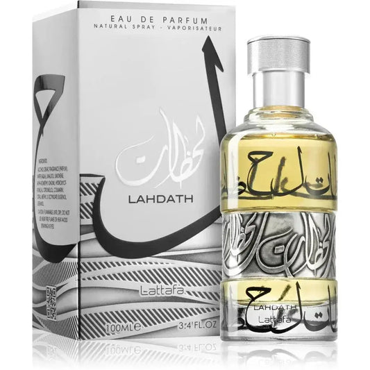 Heldere glazen fles lattafa parfum lahdath met zilveren dop en zwarte arabische kalligrafie gevuld met goudgele vloeistof