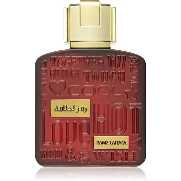 Een diep rood parfumflesje van lattafa ramz gold met gouden dop en reliëftekst hot en love