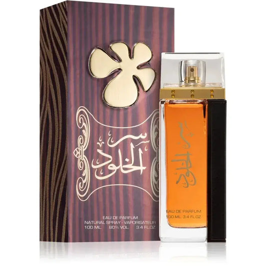 De lattafa ser al khulood eau de parfum met amberkleurige inhoud en goudkleurige spray naast paarse doos met arabische kalligrafie
