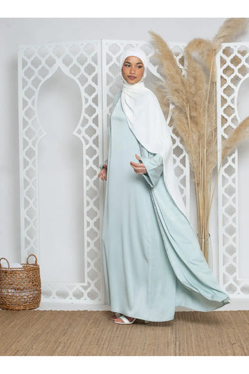 Een luxe abayaset strass met een lichtblauwe abaya van gladde stof en subtiele versieringen langs de zijnnaad met een witte hijab