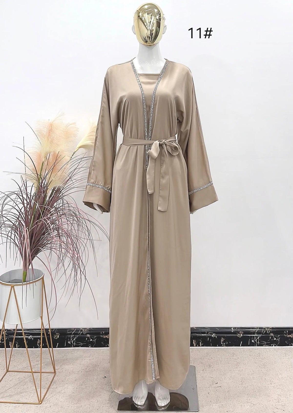 Beige satijnen abaya met zilveren kralenafwerking langs de voorkant, mouwen en taille riem van luxe abayaset strass