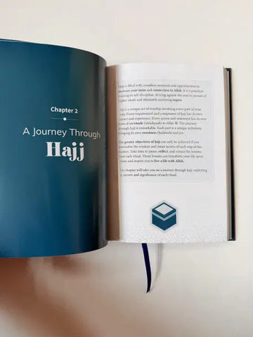 Een glanzend navy blue hardcover boek my hajj companion open bij hoofdstuk 2 een reis door de hajj met witte tekst en een geometrisch pictogram