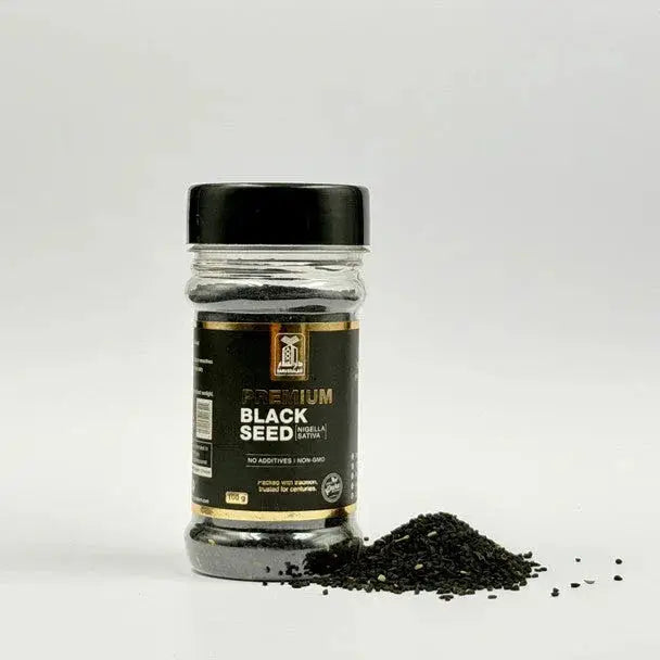 Een heldere glazen pot met zwart deksel en goudomrand label met premium zwarte zaadjes nigella sativa 100g zonder toevoegingen en non gmo