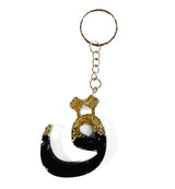 Zwart en goudkleurige resin sleutelhanger in de vorm van de arabische letter ج met metalen ring en ketting