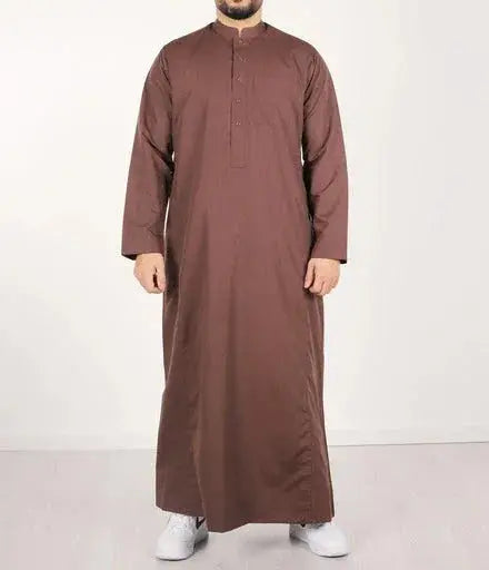 Een man draagt een lange bruine traditionele qamis ind24 met knoopsluiting en mouwen over de volledige lengte