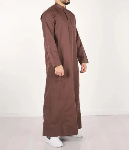 Een man draagt een lange bruine traditionele qamis met opstaande kraag en knoopsluiting van Q4him