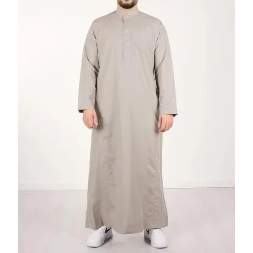 Een man draagt een lichtgrijze, floor-length qamis IND24 traditionele lange mouwen met opstaande kraag en knoopsluiting