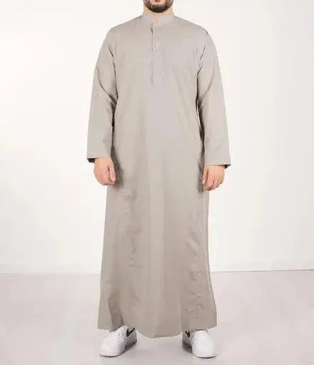 Een man draagt een lichtgrijze, floor-length qamis IND24 traditionele lange mouwen met opstaande kraag en knoopsluiting