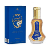 Een gouden glazen parfumfles met gouden dop en blauwe label met witte madeliefjes van alrehab crown perfumes aroosah