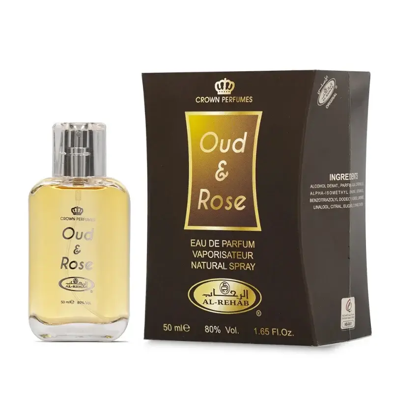 Een heldere glazen fles crown perfumes oud en rose eau de parfum met zilveren spray en goudkleurige vloeistof naast donderbruine verpakking al-rehab parfum oud en rose