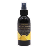 Zwarte glazen roomspray met zwarte spraydop en goudkleurig etiket ancient wisdom agarwood ambiance op gele achtergrond