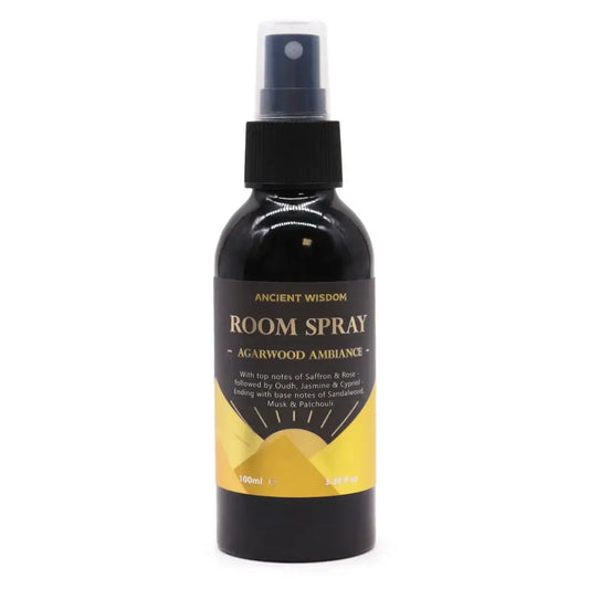 Zwarte glazen roomspray met zwarte spraydop en goudkleurig etiket ancient wisdom agarwood ambiance op gele achtergrond