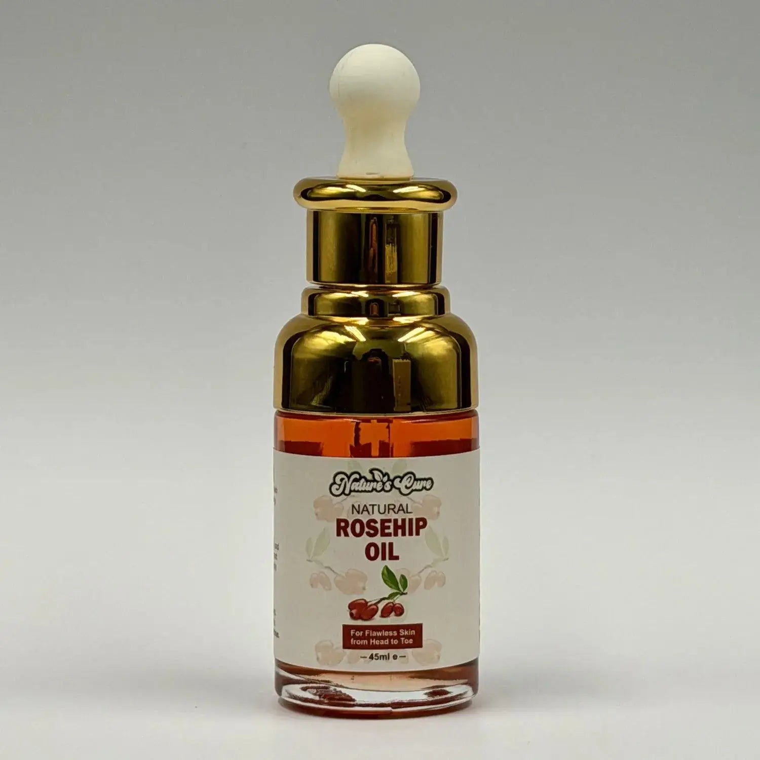 Een slanke transparante glazen fles met gouden druppelaar en amberkleurige biologische rozenbottelolie 45ml