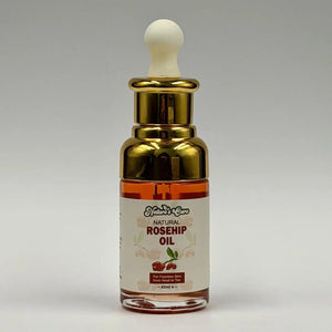 Een slanke transparante glazen fles met gouden druppelaar en amberkleurige biologische rozenbottelolie 45ml