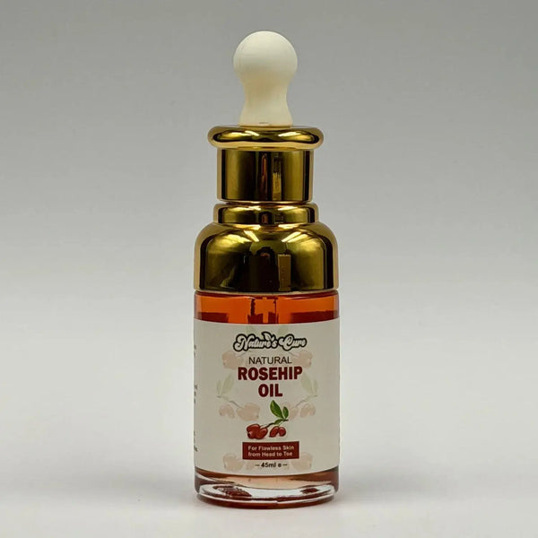 Een slanke transparante glazen fles met gouden druppelaar en amberkleurige biologische rozenbottelolie 45ml