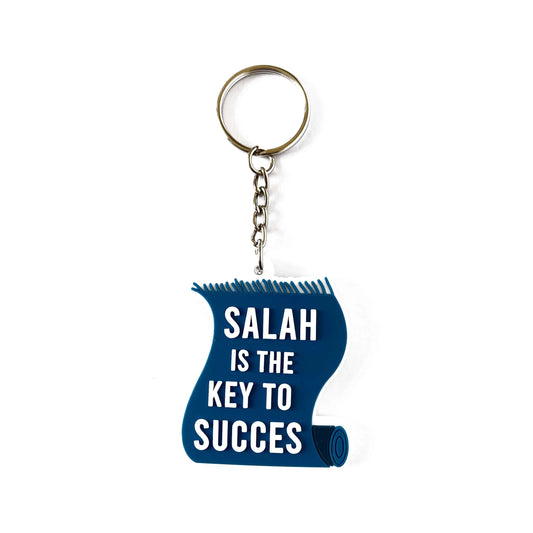 Blauwe acryl sleutelhanger in de vorm van een opgerolde rol met witte tekst salah is the key to succes en versleten rand